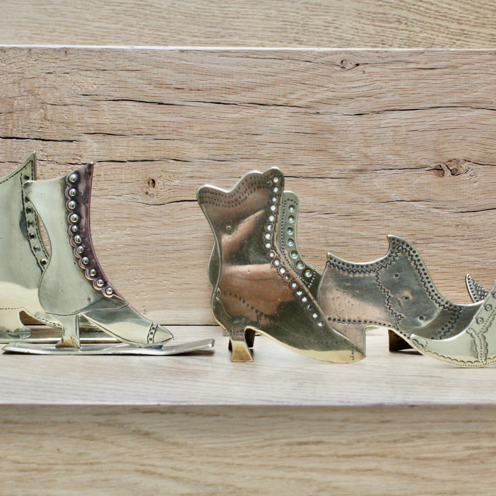
                  
                    a collection of antique folk art mantlepiece brass boots and shoes
                  
                