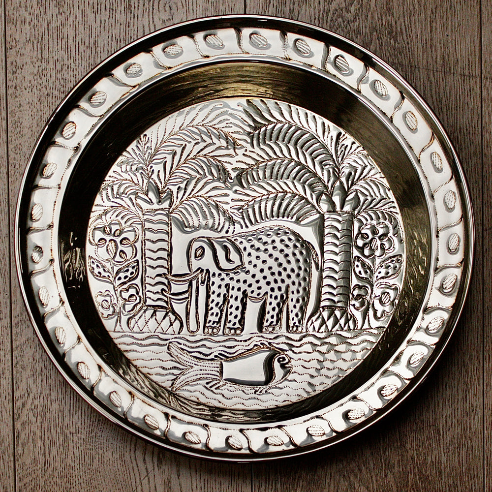 an african, efic brass charger with an elephant ,palm, flora and fish.