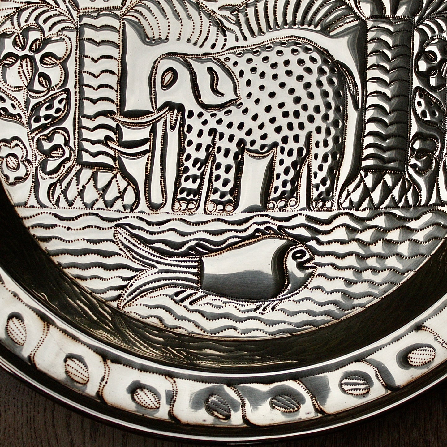
                  
                    an african, efic brass charger with an elephant ,palm, flora and fish.
                  
                