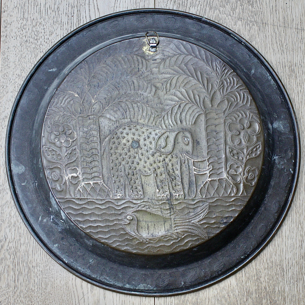 
                  
                    an african, efic brass charger with an elephant ,palm, flora and fish.
                  
                