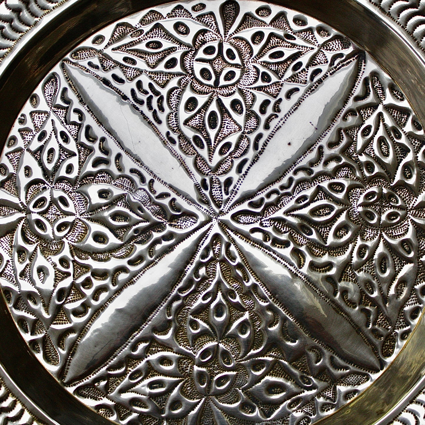 
                  
                    an antique brass embossed charger decorated with wild plants.
                  
                
