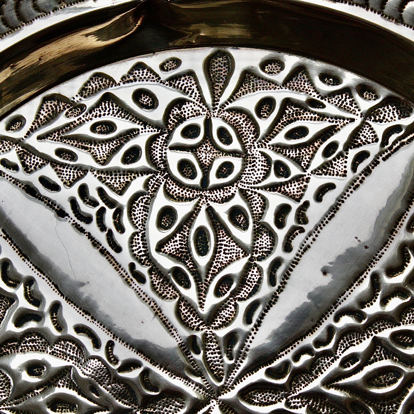 
                  
                    an antique brass embossed charger decorated with wild plants.
                  
                