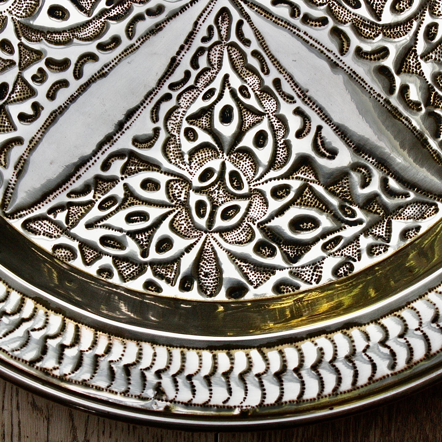 
                  
                    an antique brass embossed charger decorated with wild plants.
                  
                