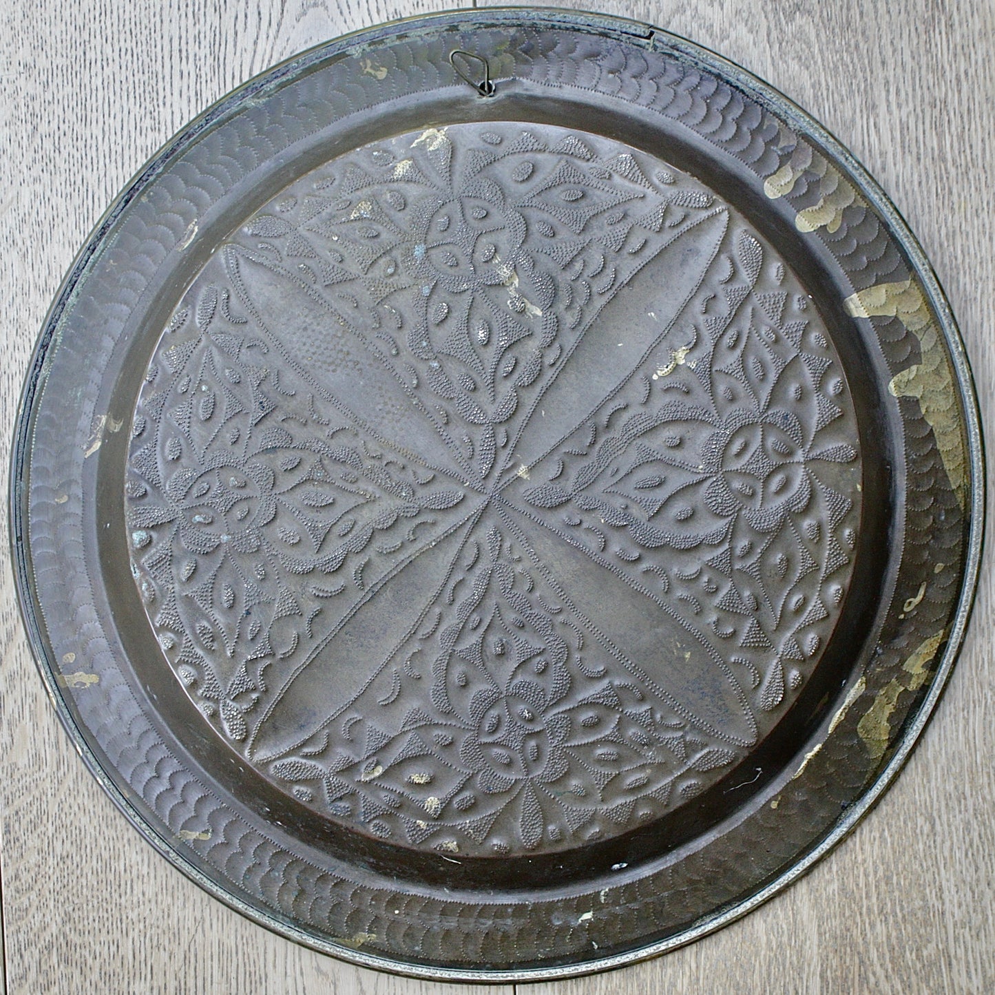 
                  
                    an antique brass embossed charger decorated with wild plants.
                  
                