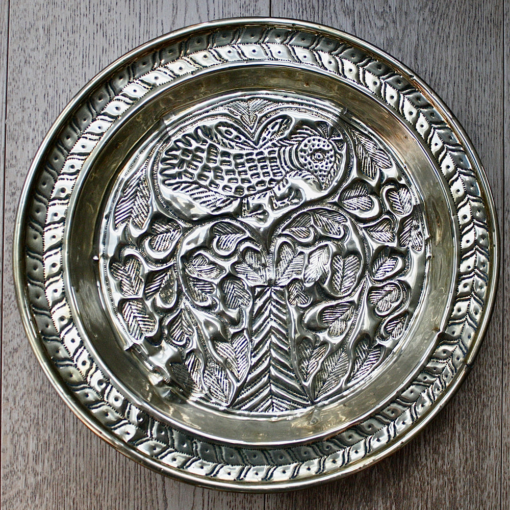 an old calabar charger decorated with a bird in a tree.