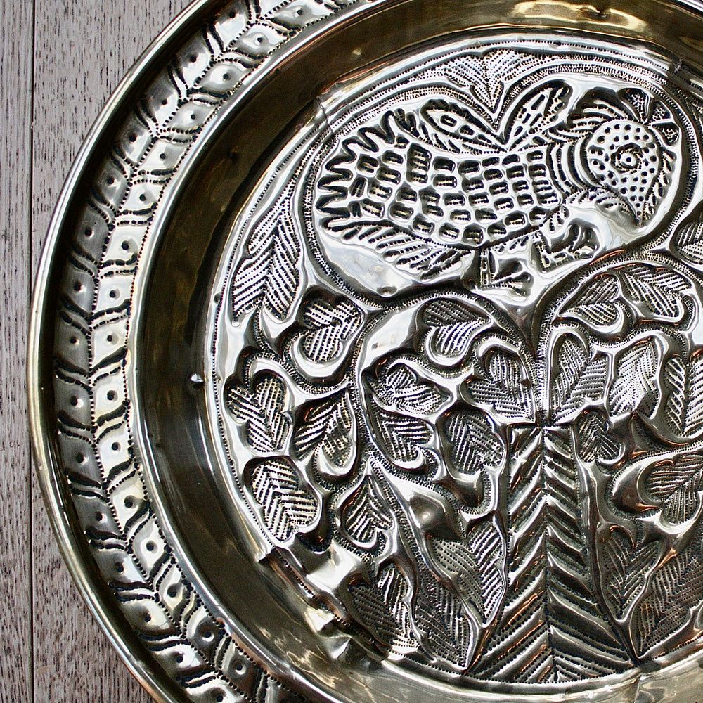 
                  
                    an old calabar charger decorated with a bird in a tree.
                  
                