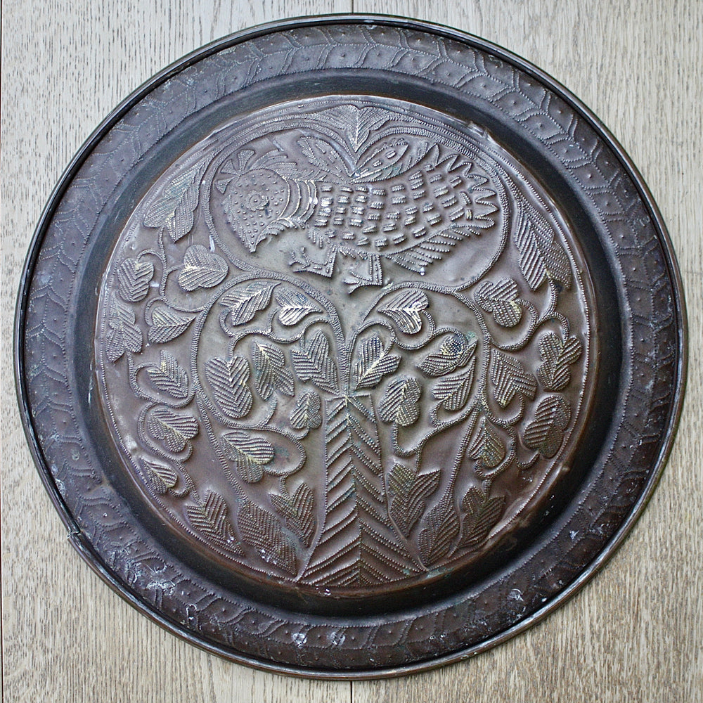 
                  
                    an old calabar charger decorated with a bird in a tree.
                  
                