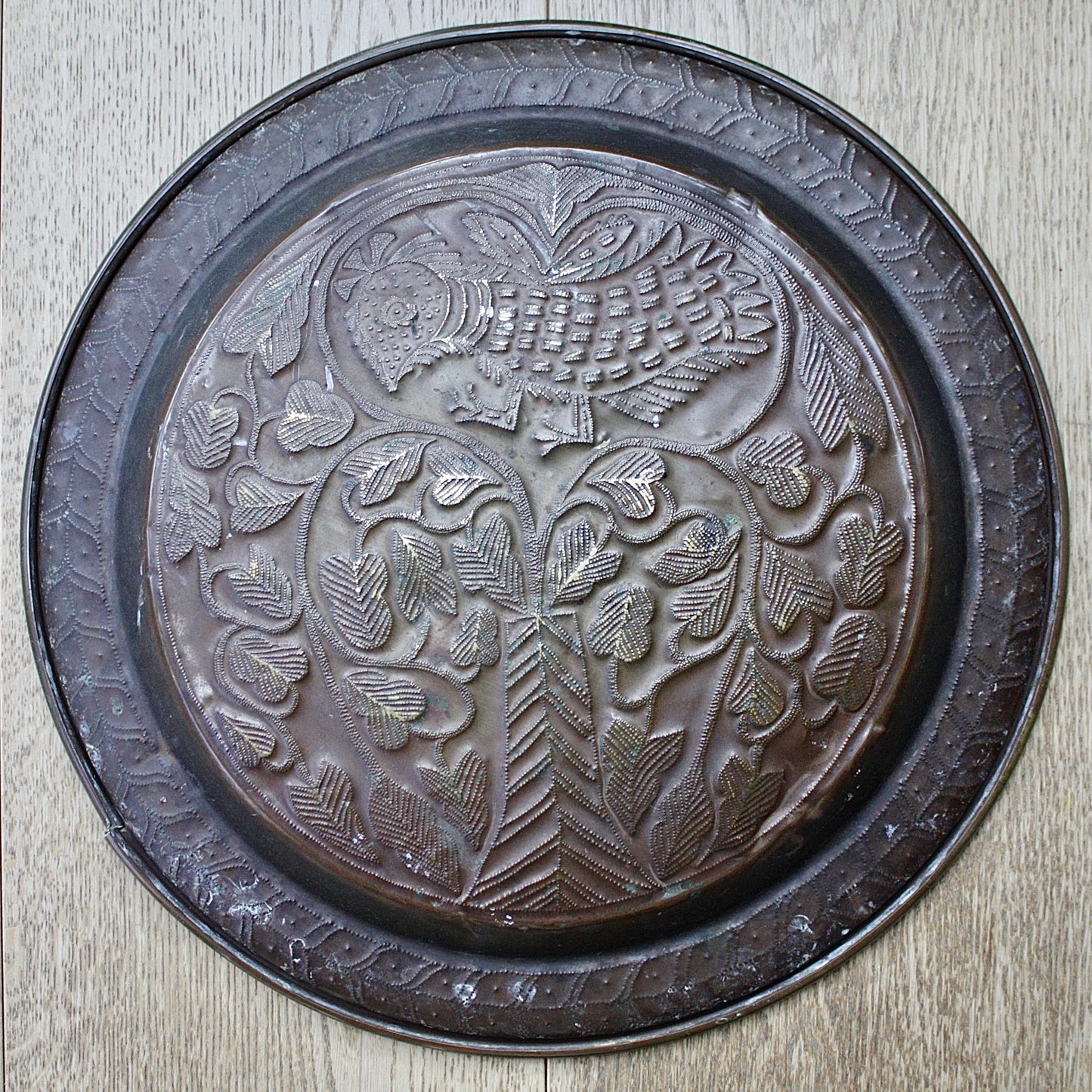 
                  
                    an old calabar charger decorated with a bird in a tree.
                  
                