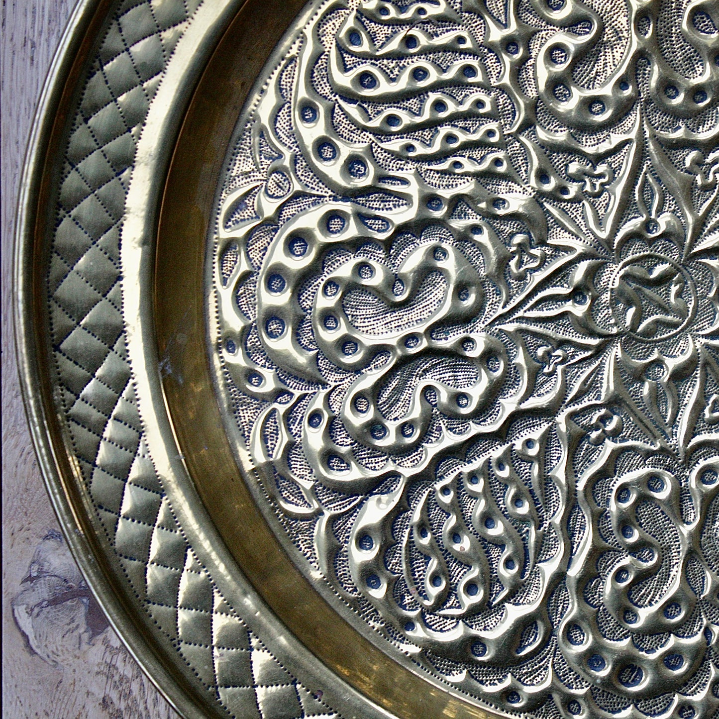
                  
                    an african efik brass charger decorated with wild plants.
                  
                
