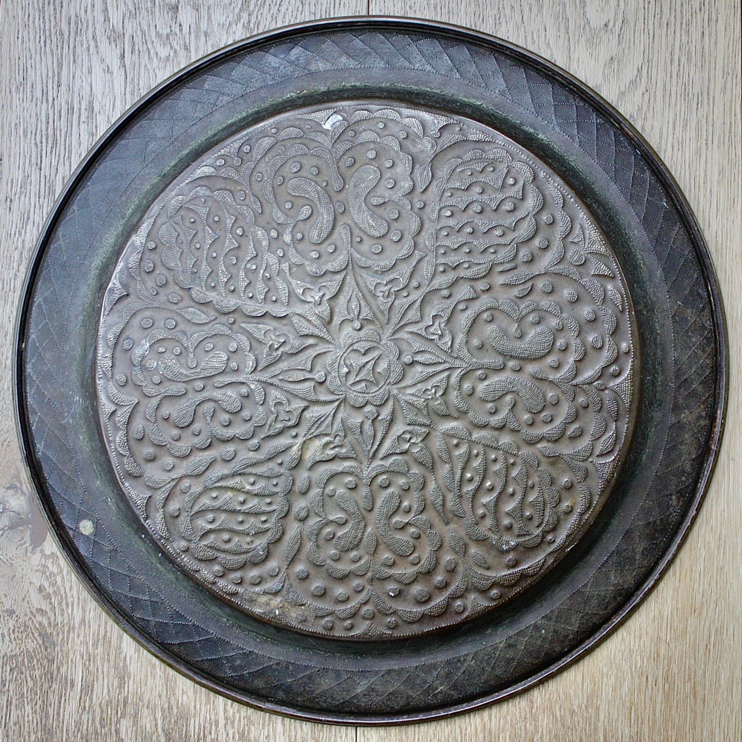 
                  
                    an african efik brass charger decorated with wild plants.
                  
                