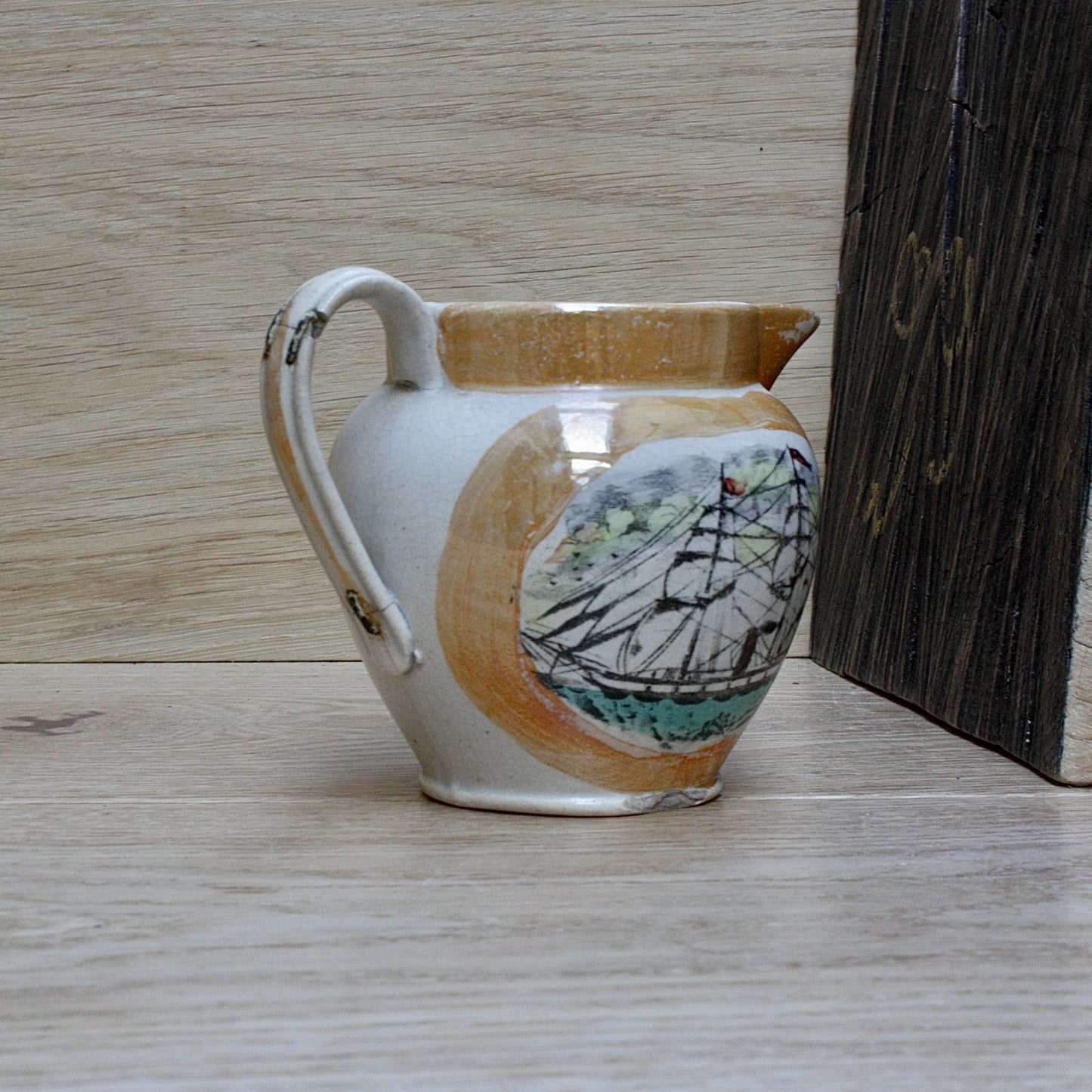 
                  
                    a small antique sunderland orange lustre jug with staple repair.
                  
                