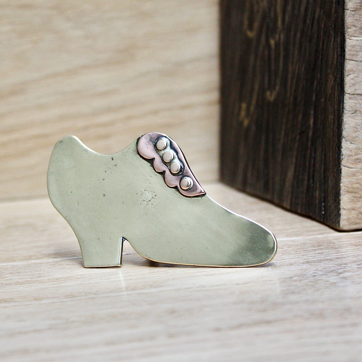 
                  
                    a small antique folk art mantlepiece brass shoe.
                  
                