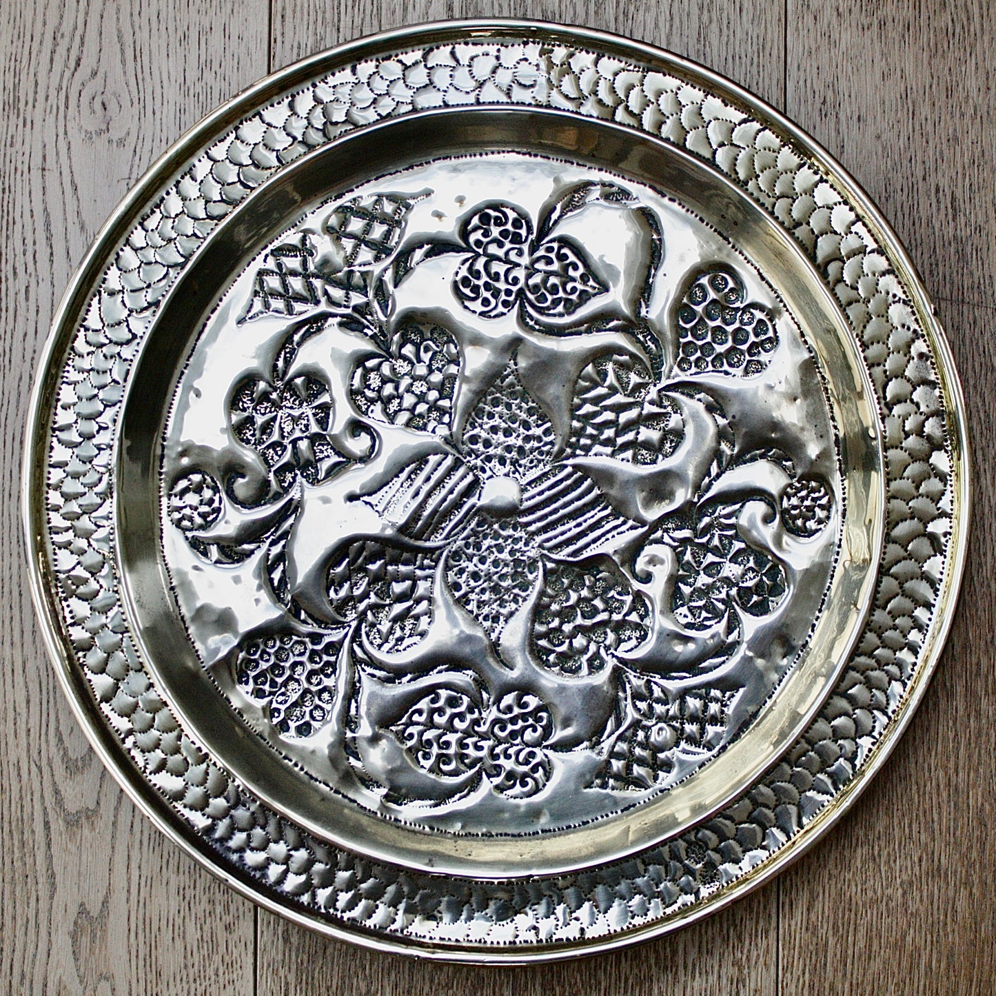 
                  
                    an african efik brass charger decorated with wild plants.
                  
                