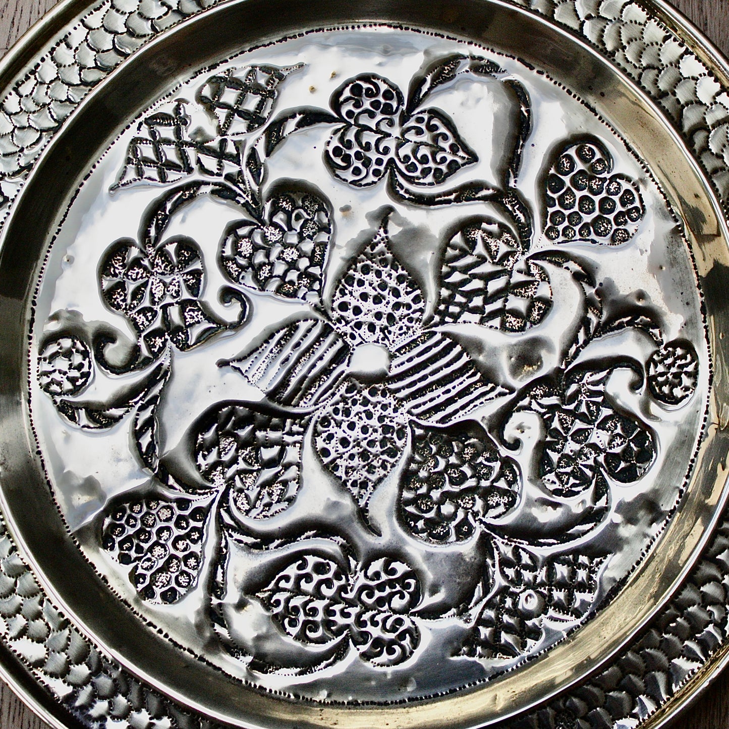 
                  
                    an african efik brass charger decorated with wild plants.
                  
                