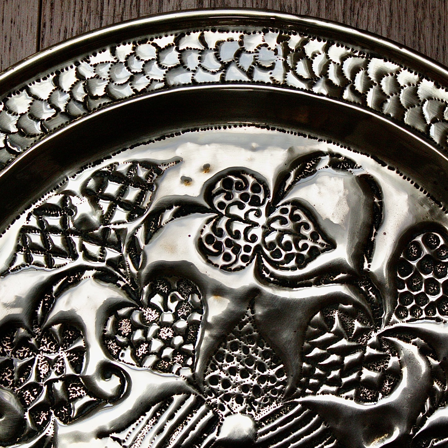 
                  
                    an african efik brass charger decorated with wild plants.
                  
                