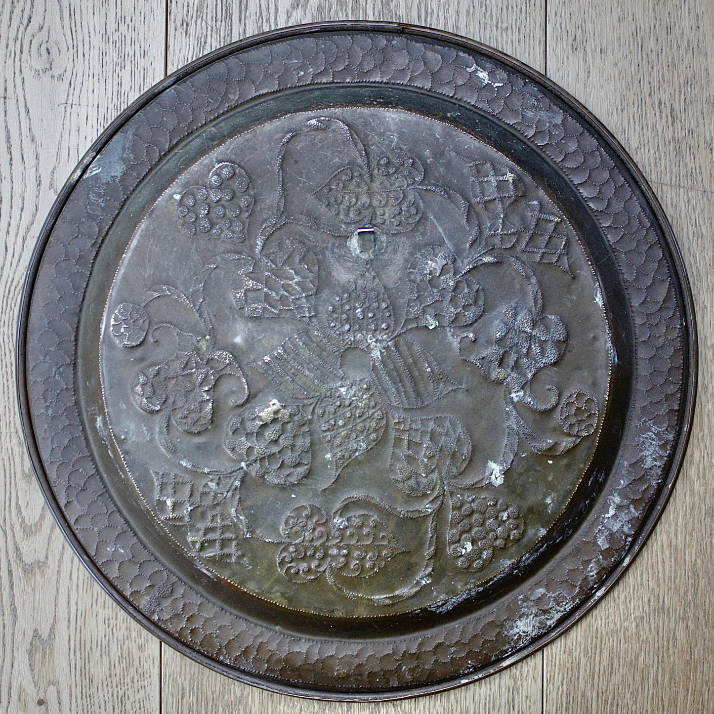 
                  
                    an african efik brass charger decorated with wild plants.
                  
                
