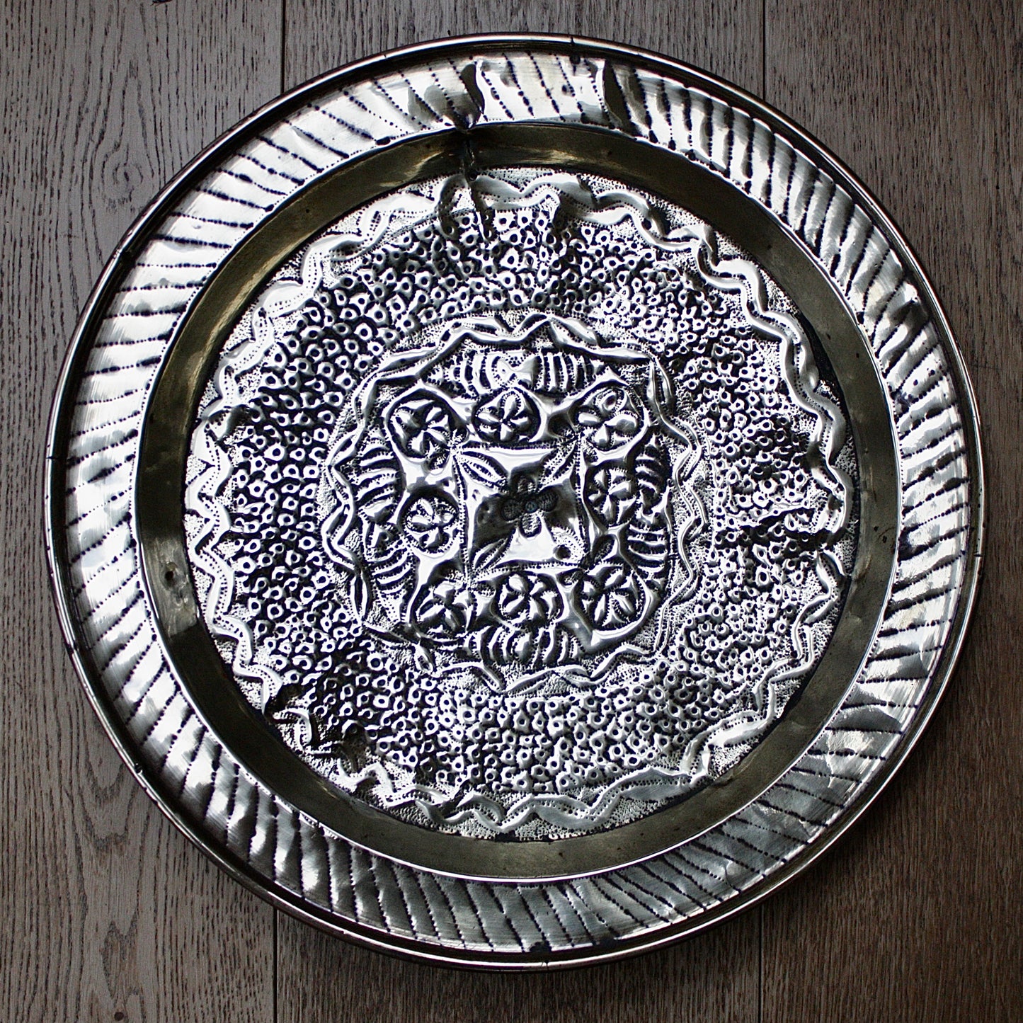 
                  
                    an african efic brass charger decorated with wild plants.
                  
                