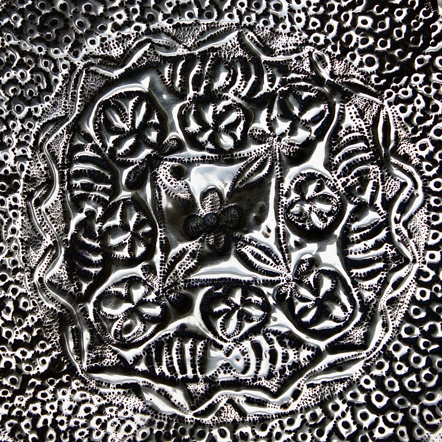 
                  
                    an african efic brass charger decorated with wild plants.
                  
                
