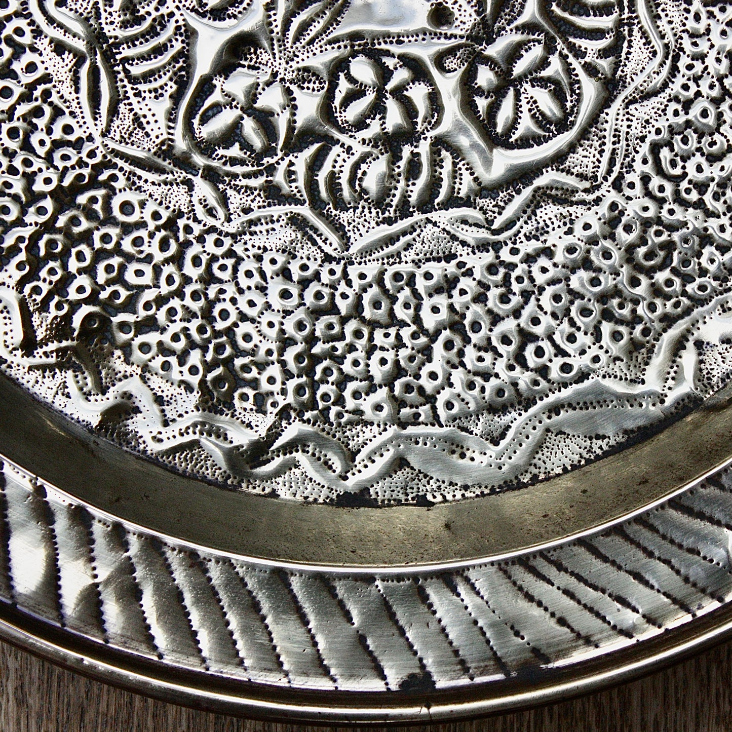 
                  
                    an african efic brass charger decorated with wild plants.
                  
                