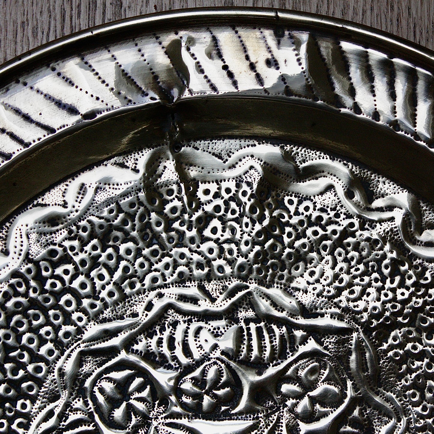 
                  
                    an african efic brass charger decorated with wild plants.
                  
                