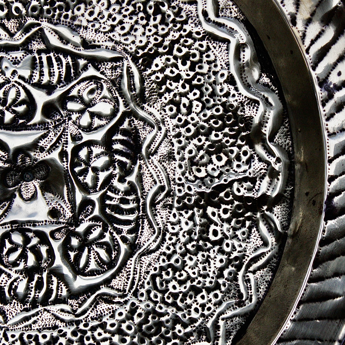 
                  
                    an african efic brass charger decorated with wild plants.
                  
                