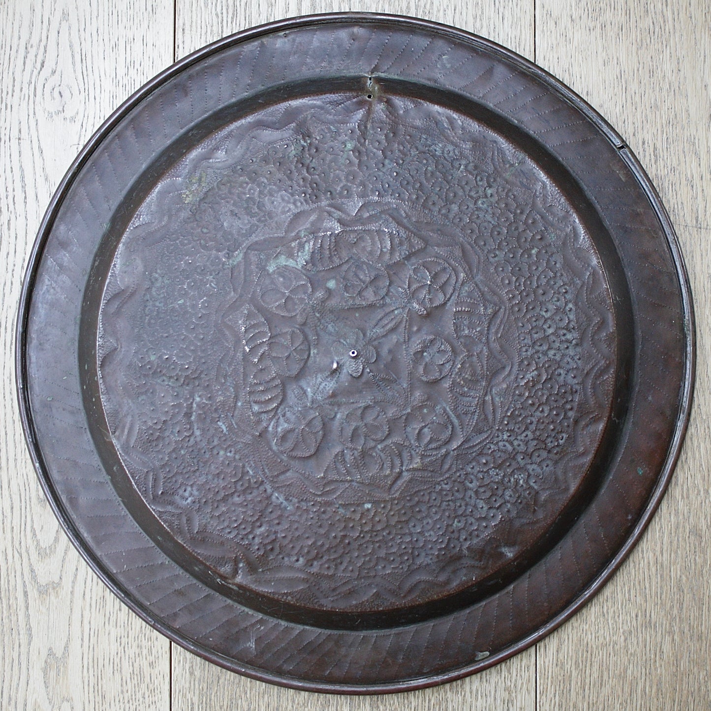 
                  
                    an african efic brass charger decorated with wild plants.
                  
                