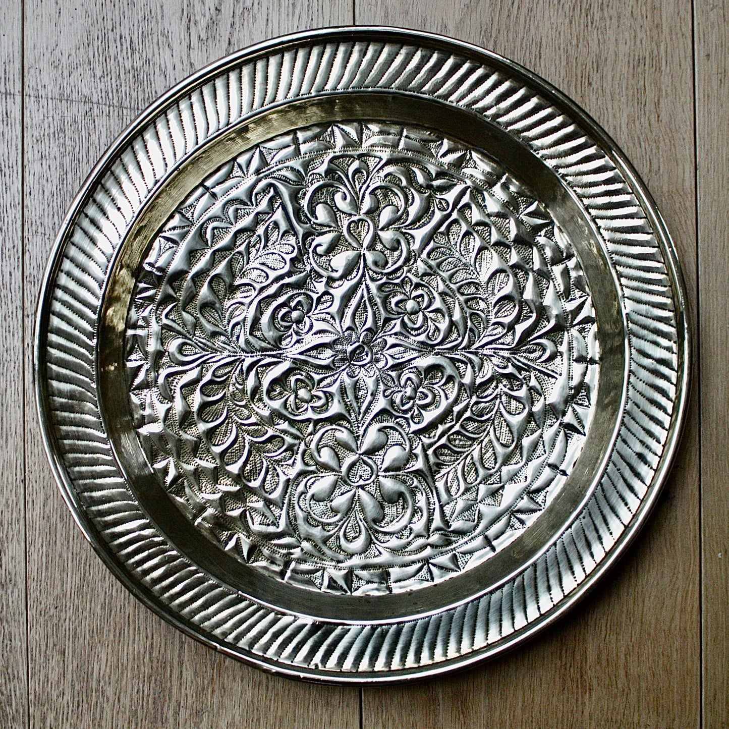 
                  
                    an african efik brass charger decorated with wild plants.
                  
                