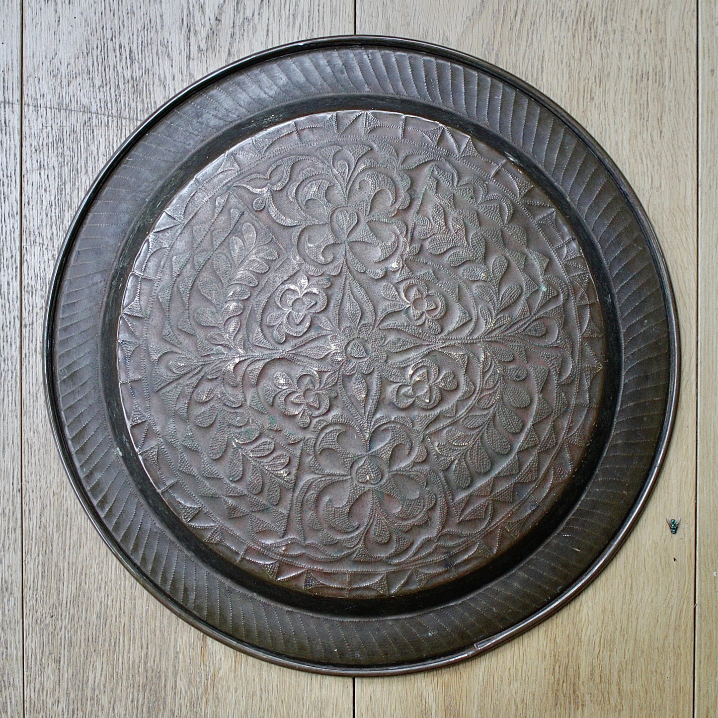 
                  
                    an african efik brass charger decorated with wild plants.
                  
                
