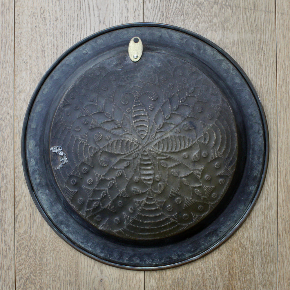 
                  
                    an antique african efic brass charger embossed with wild plants
                  
                